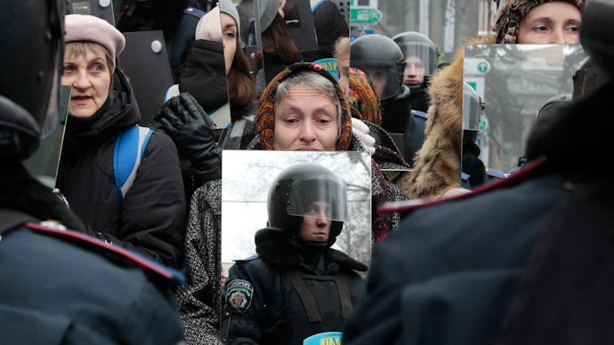Ukranian protestor holds up a mirror to the police in riot gear