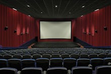 An empty movie theater with the lights turned on and the screen empty