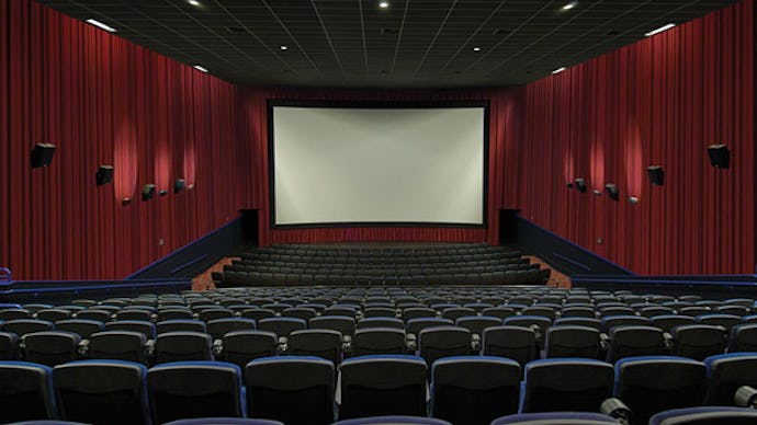 An empty movie theater with the lights turned on and the screen empty