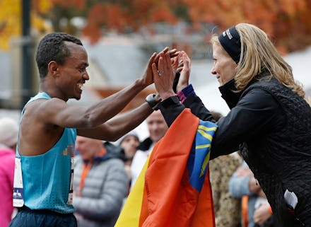 A marathon runner smiling and high-fiving a woman from the audience