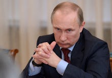 Vladimir Putin, President of Russia, sitting with his fingers intertwined.