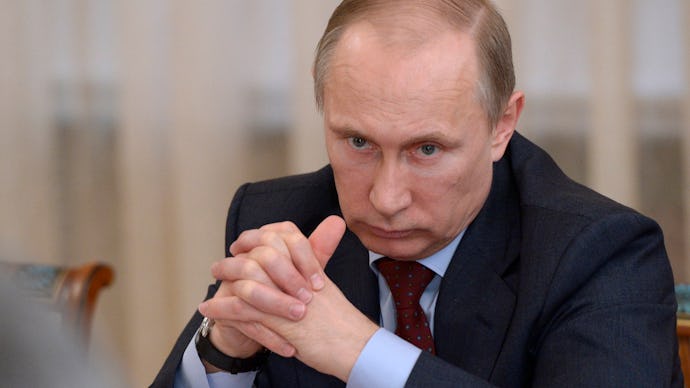 Vladimir Putin, President of Russia, sitting with his fingers intertwined.