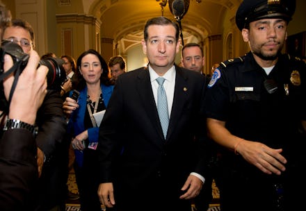 Ted Cruz walking down a hall with reporters taking pictures and asking him questions as he's escorte...