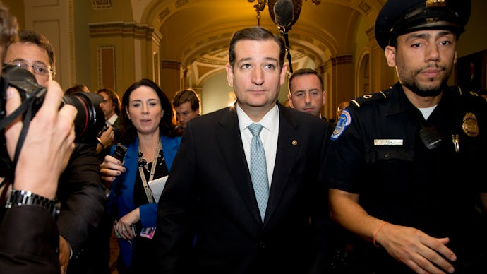 Ted Cruz walking down a hall with reporters taking pictures and asking him questions as he's escorte...