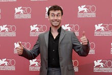 James Deen in a grey suit and a black shirt at a red carpet event