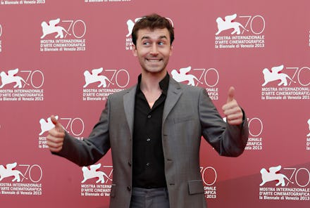 James Deen in a grey suit and a black shirt at a red carpet event