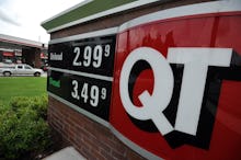 A large red and with sign with Gas Prices that are finally down in front of a gas station