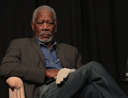 Morgan Freeman sitting in a chair with his legs crossed and a white glove on his left hand