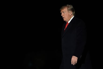 Donald Trump walking, looking angry with a black background behind him, in a black suit with a white...