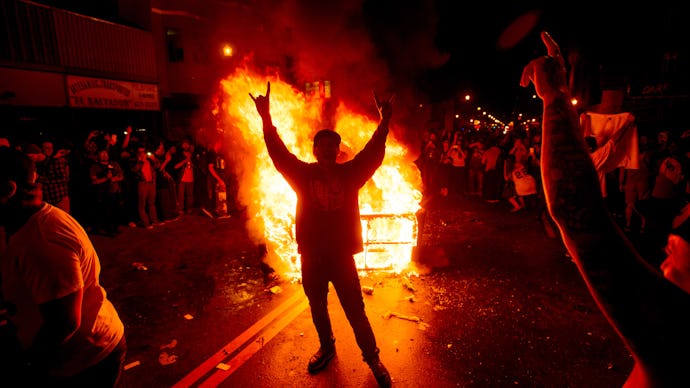 A group of fans rioting after a championship team while a fire rages on the street