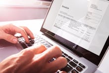 Close up of a pair of hands, working on an invoice on a laptop.