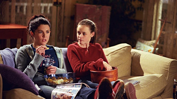 Lorelai and Rory from 'Gilmore Girls' sitting on a couch and eating popcorn