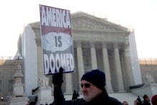 Protestor holding a sign that says America is doomed