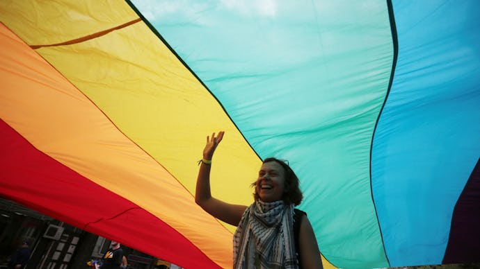 A woman walking underneath a large pride flag