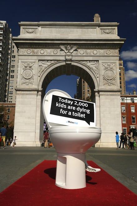 A toilet with the sign today 2000 kids are dying for a toilet placed in front of the Arc de Triomphe