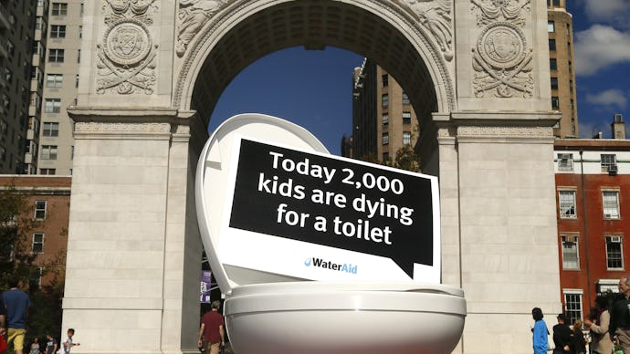 A toilet with the sign today 2000 kids are dying for a toilet placed in front of the Arc de Triomphe