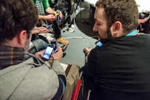 Men talking while looking at their phones at the Startup Live event.