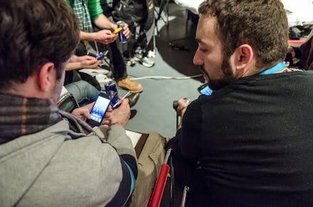 Men talking while looking at their phones at the Startup Live event.