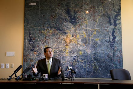 A man sitting during a speech with microphones in front of him