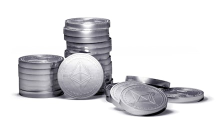 Silver coins, some stacked up on one another, some on the side, on their own, representing Ethereum