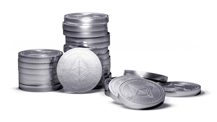 Silver coins, some stacked up on one another, some on the side, on their own, representing Ethereum