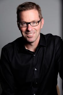 Hugo Schwyzer, a male feminist, in a black shirt and glasses standing and smiling