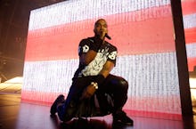 Kanye West performing and kneeling on stage during a concert