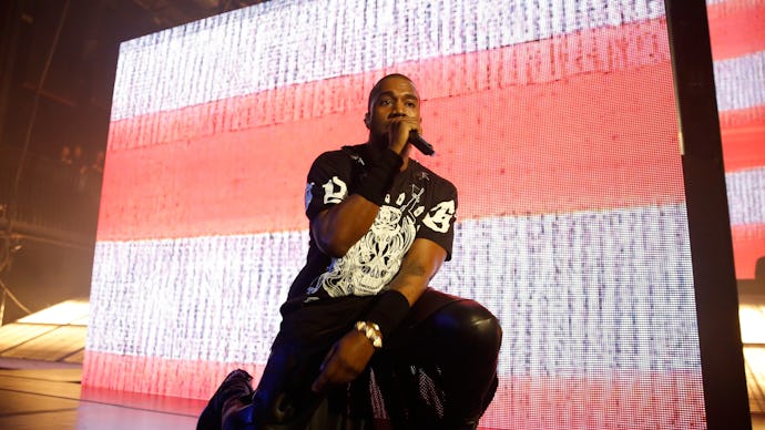 Kanye West performing and kneeling on stage during a concert