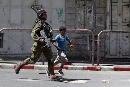 IDF soldier and a kid running across the street while tensions rise in the West Bank