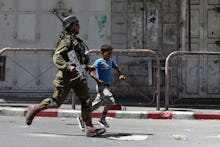 IDF soldier and a kid running across the street while tensions rise in the West Bank