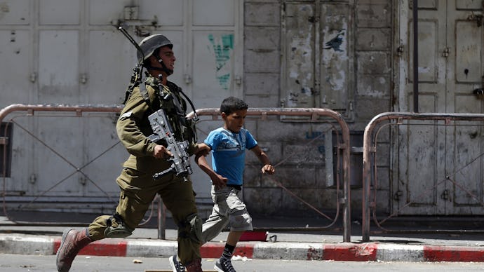 IDF soldier and a kid running across the street while tensions rise in the West Bank