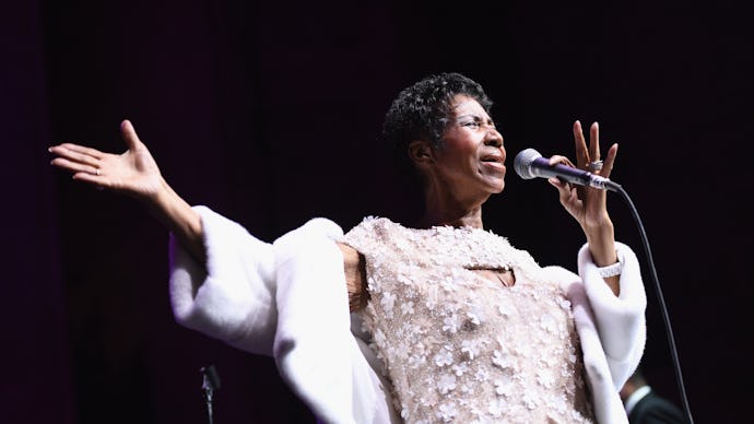 Aretha Franklin in a white floral dress and a white coat performing