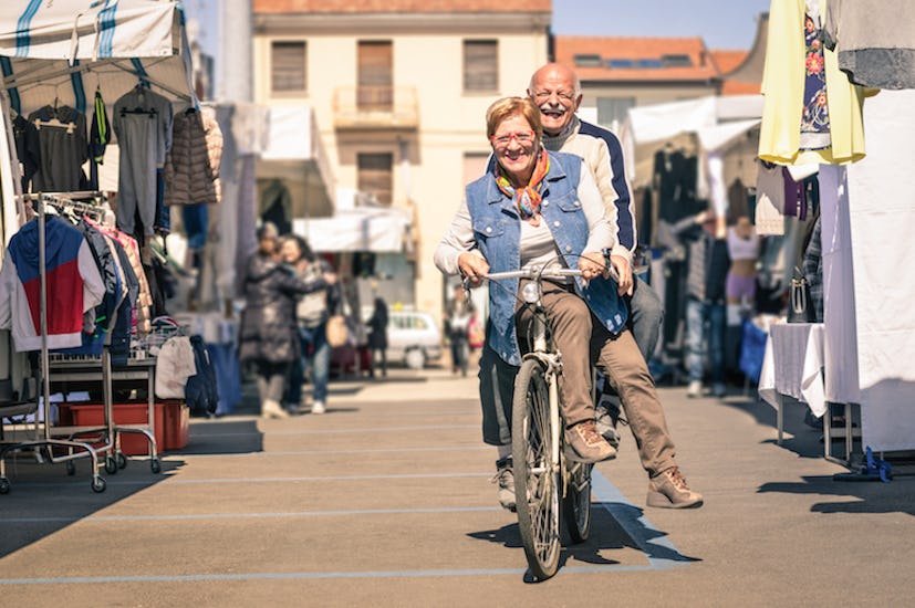 An older couple riding a bike through the streets while laughing