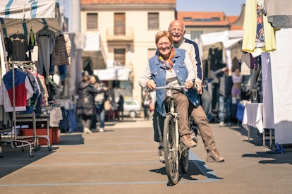 An older couple riding a bike through the streets while laughing