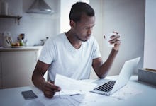 A man drinking coffee and looking at his 401(k) list on his laptop 