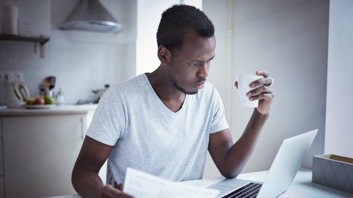 A man drinking coffee and looking at his 401(k) list on his laptop 