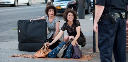 A cop confronting two women who are selling duplacte purses on the street