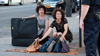 A cop confronting two women who are selling duplacte purses on the street