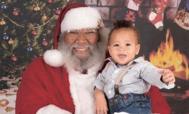 The black New Orleans Santa posing with a little child on his lap, both smiling
