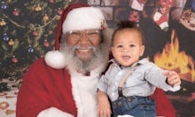 The black New Orleans Santa posing with a little child on his lap, both smiling