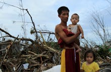 A family standing in the aftermath of typhoon haiyan in the philippines