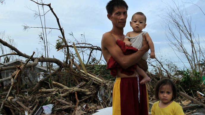 A family standing in the aftermath of typhoon haiyan in the philippines