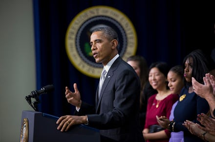 Barack Obama during a speech with a group of people standing behind him