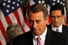 John Boehner in a black suit, and a white shirt and the American flag in the background