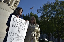 Two women near the Dakota Access Pipeline holding a poster with the text 'Clean water is national se...