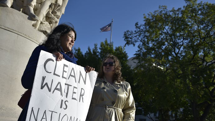 Two women near the Dakota Access Pipeline holding a poster with the text 'Clean water is national se...