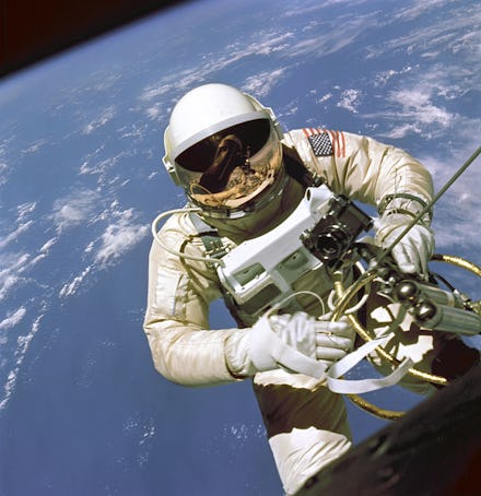 An astronaut on the outside of a space station with earth behind him