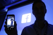 A man showing a Facebook post and a Facebook logo behind his back