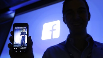 A man showing a Facebook post and a Facebook logo behind his back