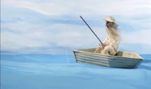 Man in white coat in the middle of the blue sea sitting in the boat and fishing from a 5-Second vide...